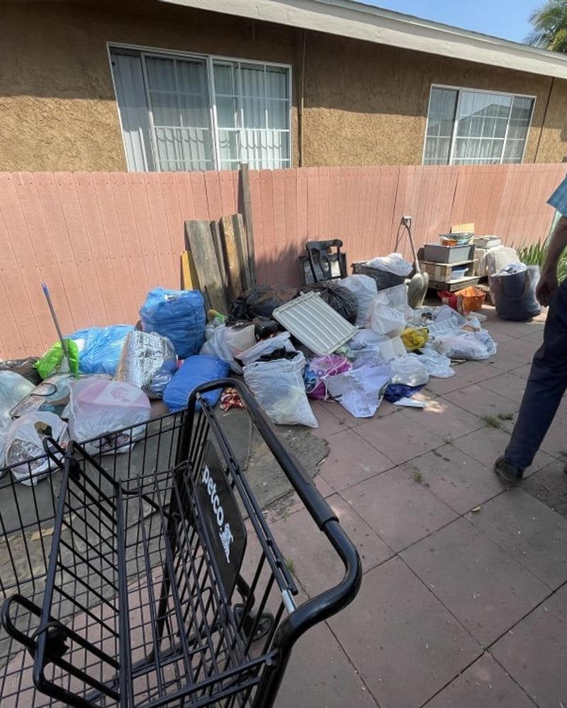Junk removal worker clearing bagged household items and furniture from a Palm Bay property