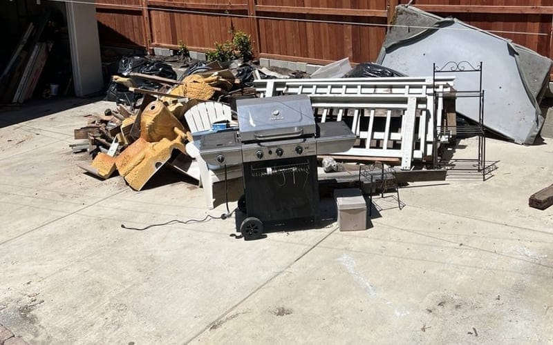 Metal framing, patio junk and yard debris cleared beside a Palm Bay fence