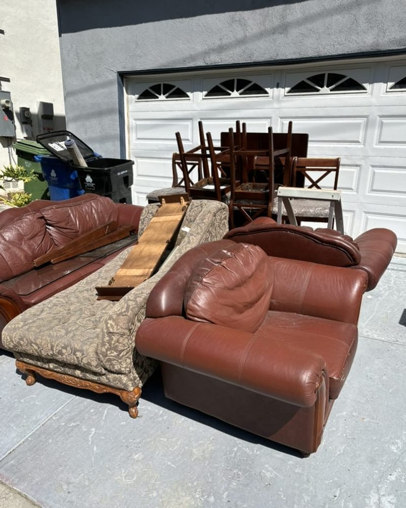 Leather sofas and dining chairs set out for furniture removal in Palm Bay
