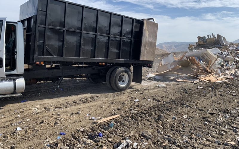 Large hauling truck loading bulk waste at a commercial site
